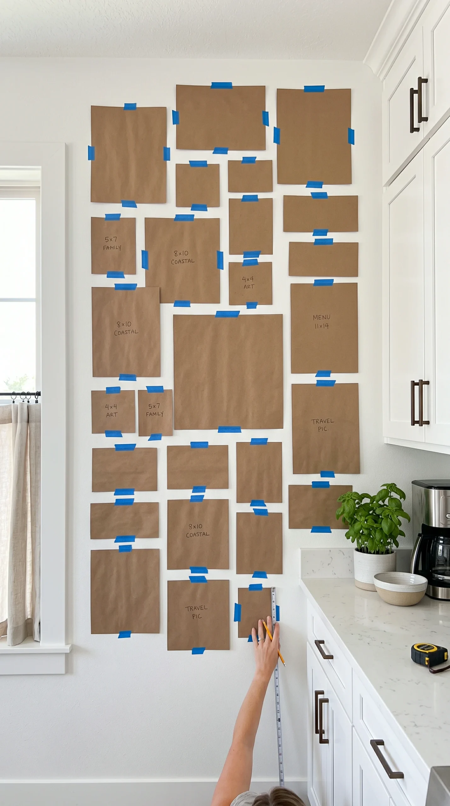 A modern kitchen wall covered in brown craft paper templates for a gallery wall layout.